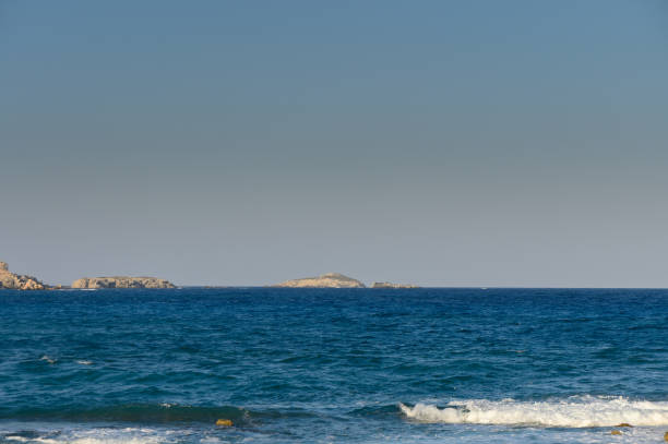 istock A serene coastal view showcasing gentle waves and distant islands under a clear blue sky. 2184225548
