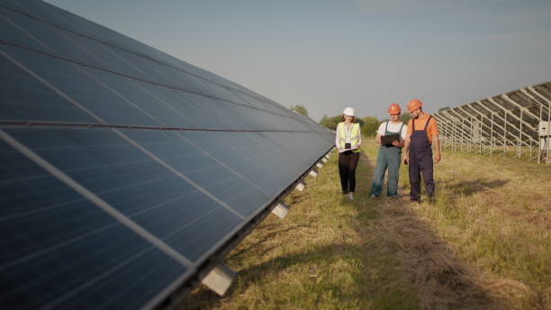 istock Business team of industrial engineers walking on solar farm and discussing efficient plan of construction. Ecological station. Alternative energy. Engineers use drawings on the solar farm 2184226045