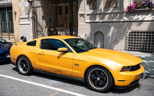 New York City, USA - August 05, 2023: 2011 Ford Mustang V6 yellow car passenger side view, parked.