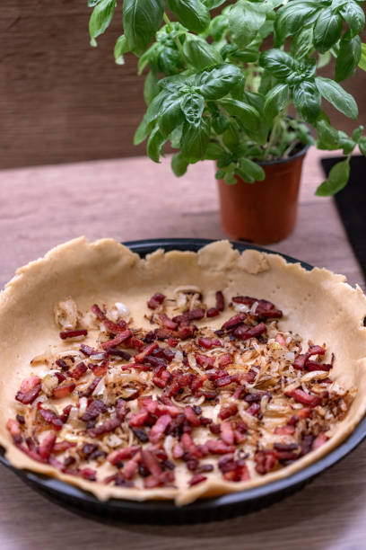 istock Dough with fried bacon and onion put in round pan to make a quiche. Baking at home. 2184229042