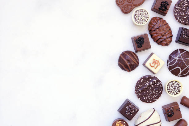 istock Chocolate side border with an assortment of fine, luxurious sweets on a white marble background 2184229427