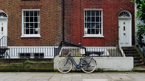 istock Blue bicycle leaning against wall in front of typical english brick house 2184231739