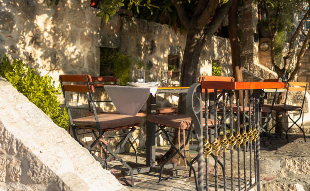 istock A charming outdoor cafe with a rustic table and chairs set under warm sunlight, offering a peaceful ambiance in a cozy courtyard surrounded by nature. 2184231901
