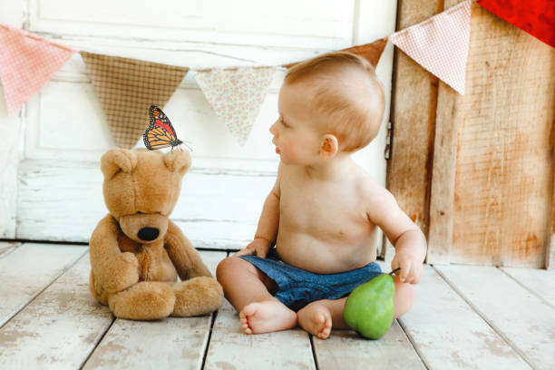 baby boy on the bed with a big teddy bear in a blue bodysuit, happy healthy little baby in the bedroom
