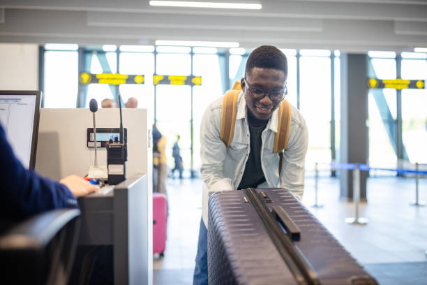 istock Man lifts suitcase onto check-in scale at counter. 2184234090