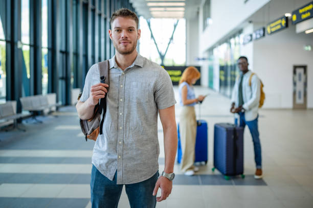 istock Man standing in airport with backpack over shoulder 2184234364