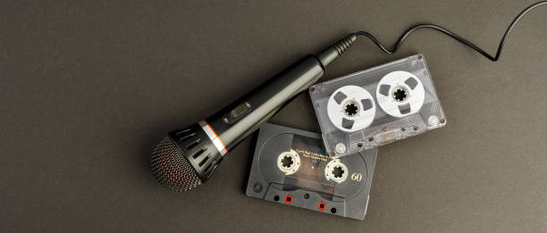istock Black professional karaoke microphone and two vintage audio cassettes on a black background with space for text. A photo suitable for a banner 2184234420