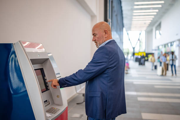 istock Man using ATM in modern airport setting indoors 2184234478