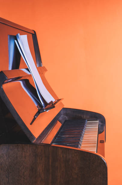 istock Polished upright piano reflecting red wall with sheet music 2184235301