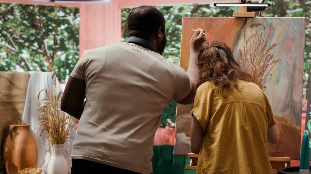 istock Talented artist and her apprentice applying watercolor paint on canvas 2184237270