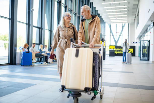 istock Seniors with luggage exploring airport terminal aisles 2184237525