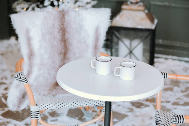 istock Cozy winter setup with mugs on a table near a chair and lantern 2184239796