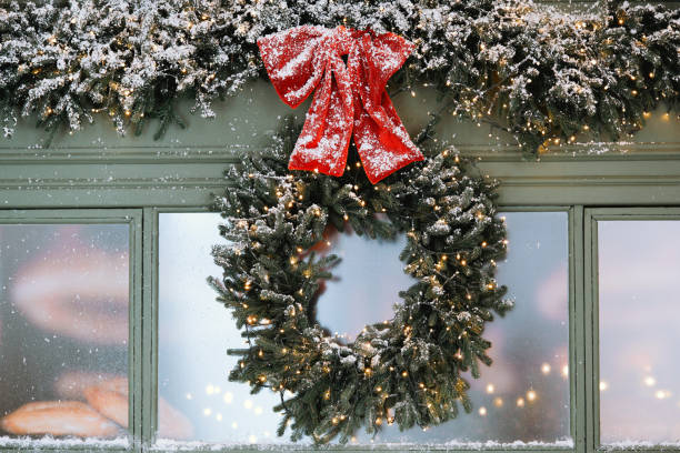 istock Snow-covered wreath with red bow adorning a window during winter festivities 2184239827