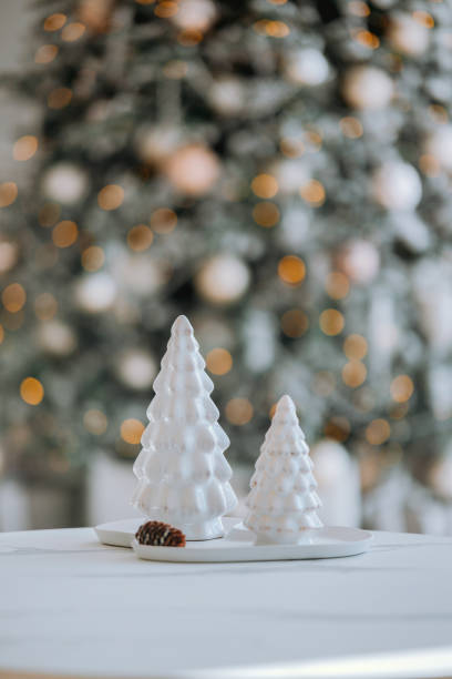 istock Elegant white ceramic Christmas trees on a table with blurred festive background 2184239847