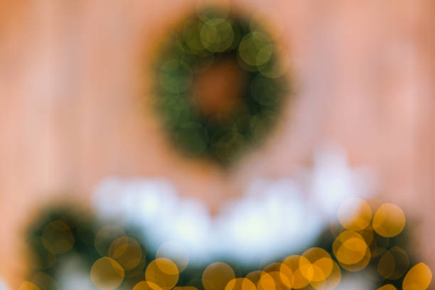 A cozy setting featuring a beautifully adorned wreath hanging on a wooden wall, surrounded by soft, warm lights creating a festive atmosphere for the holiday season.