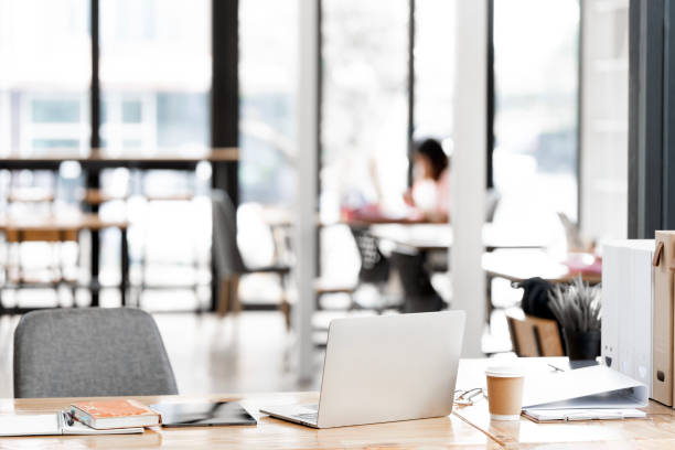 istock Rear view of simple workspace with laptop, notebooks, coffee cup and tree pot on white table with blurred office room background 2184240668