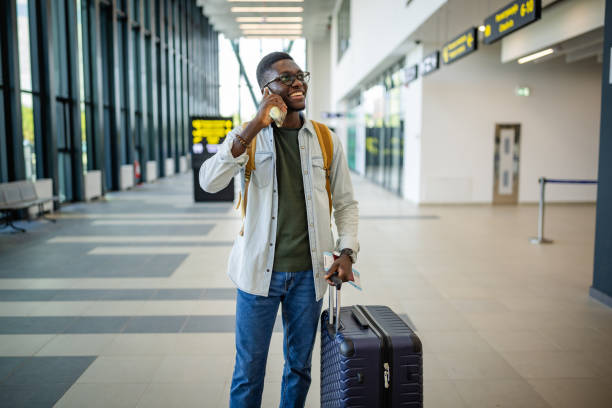 istock Traveler smiling and chatting on phone at terminal. 2184241543