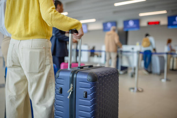 istock Traveler with blue suitcase in airport check-in line 2184241764