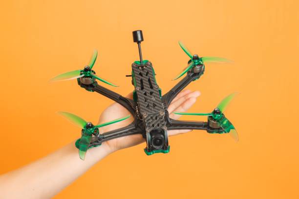 istock Hands holding professional modern drone with camera on orange background 2184243691