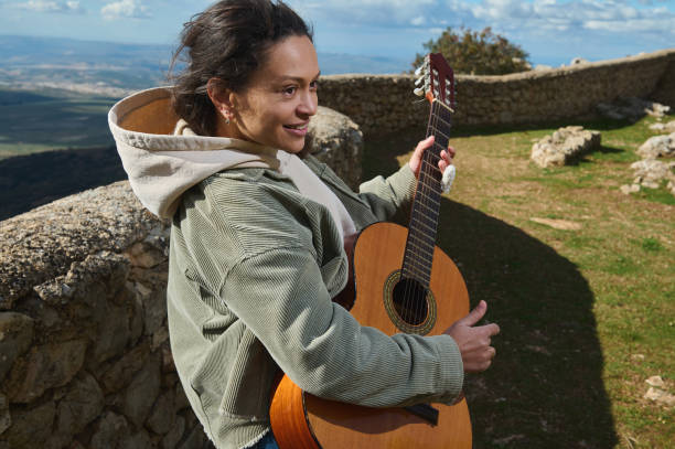 istock Woman enjoying a scenic view while playing guitar on a sunny day 2184252169