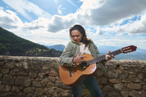 istock Woman strumming guitar outdoors with scenic mountain backdrop 2184252170