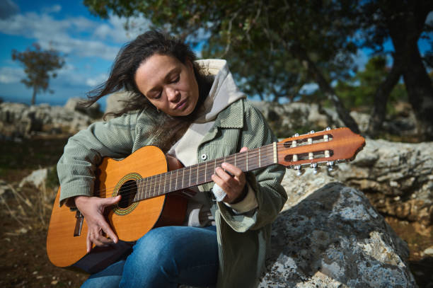istock Woman playing acoustic guitar outdoors on a sunny day 2184252173
