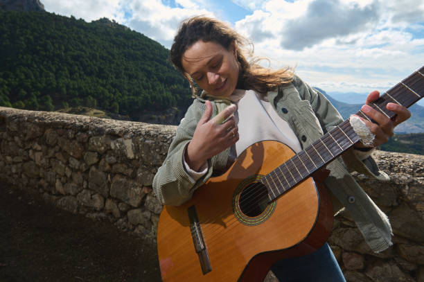 istock Woman playing guitar outdoors with scenic mountain backdrop 2184252177