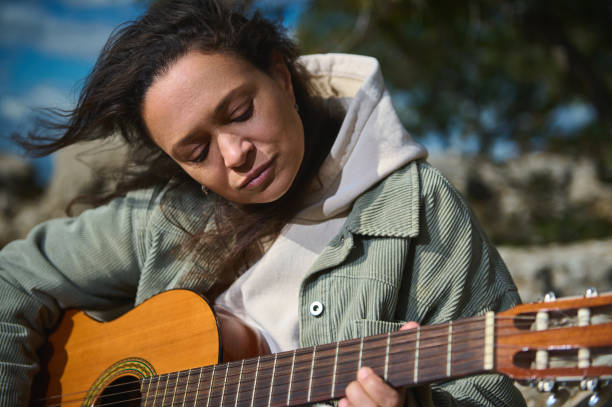 istock Woman playing guitar outdoors on a windy day 2184252184