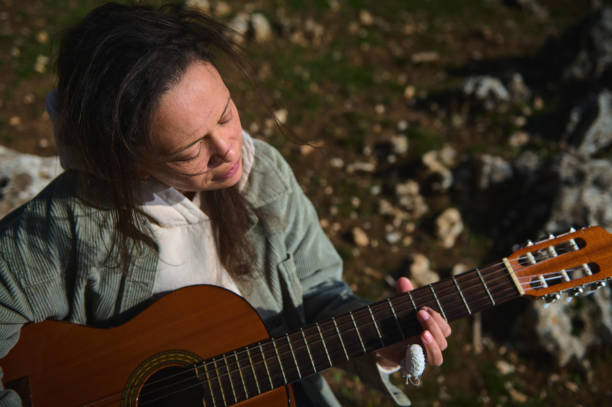istock Woman playing acoustic guitar outdoors in serene natural setting 2184252196