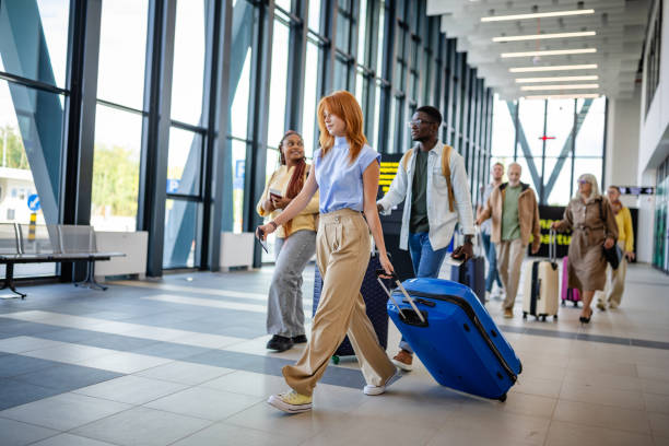 istock Travelers walking through a bright airport terminal. 2184253495