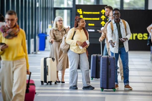 istock Travelers with luggage queue at airport terminal gate. 2184254841