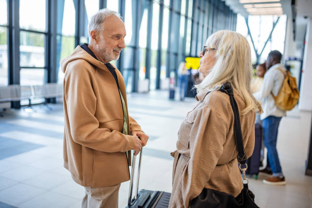 istock Two Seniors Conversing at a Bright Modern Airport 2184255726