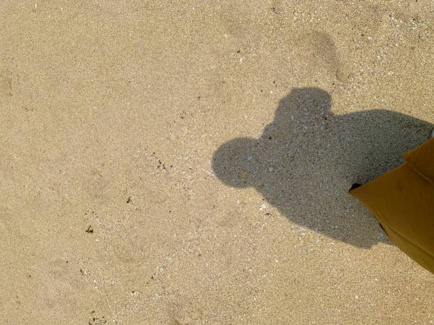istock A solitary figure casts a long shadow on a sandy beach 2184260834