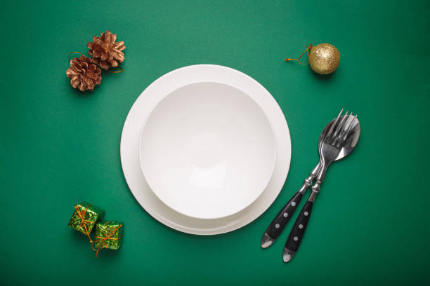 istock Christmas table setting featuring empty plate, cutlery, festive decorations on green background 2184264206