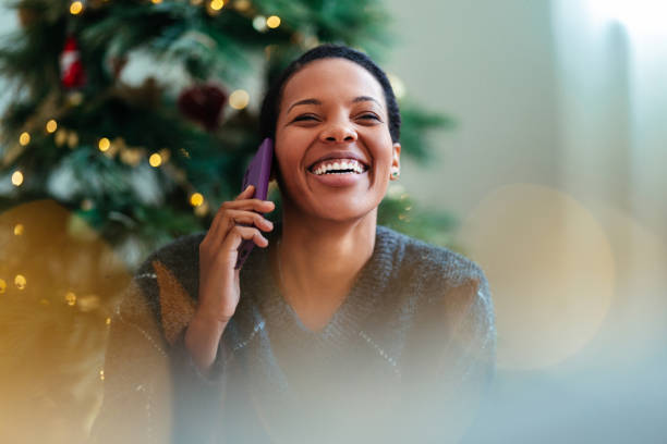 Joyful Woman Talking on Phone by the Christmas Tree