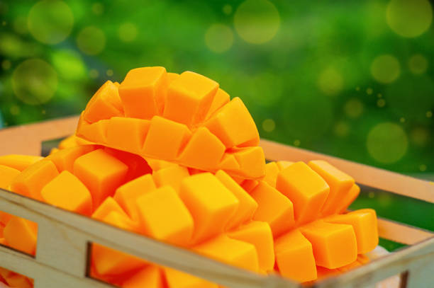 Cutted artificial fruits of orange ripe mango. There are multi-colored bokeh effect elements around the edges of the frame. Imitation of food, crop time, harvesting concept.