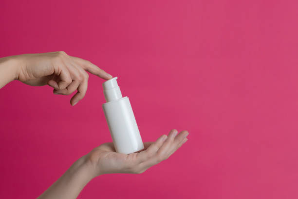 istock White unbranded cream bottle with pump in hand on pink background. Natural moisturizing, nourishing cosmetics for skin, beauty and spa 2184268480
