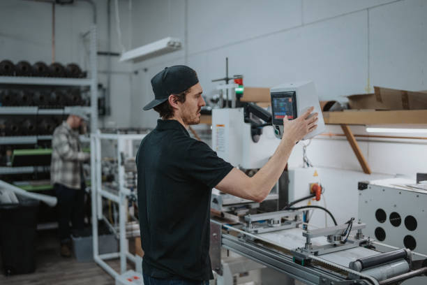 A man uses a touch screen computer monitor when inputing setting on an automated embroidery machine located in his family's manufacturing and fabrication facility.