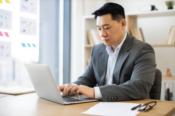 istock Asian businessman in office working on laptop at desk 2184270216