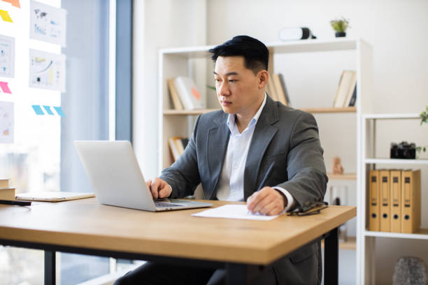 istock Focused Asian businessman working on laptop in modern office 2184270221