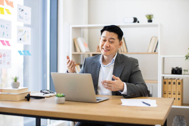 istock Asian businessman conducting online video call in modern office setting 2184270253