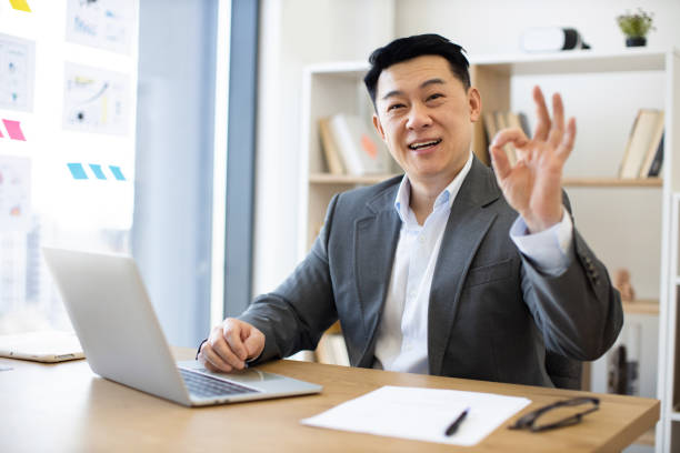 istock Asian businessman working in office with laptop and making okay gesture 2184270255