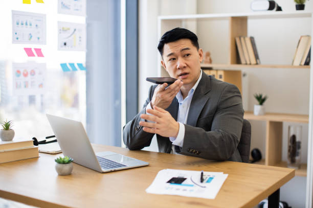 istock Asian businessman recording audio messages in modern office setting 2184271379