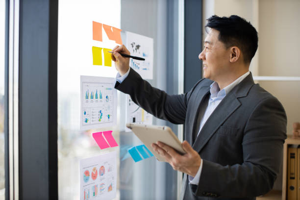 istock Asian businessman analyzing charts on window with digital tablet 2184271411