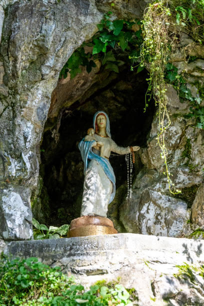 istock Madonna statue in a rocky niche surrounded by lush vegetation. 2184274490