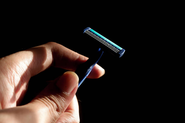 istock A man's hand holds a mustache shaver with sharp blades on a dark background 2184276459
