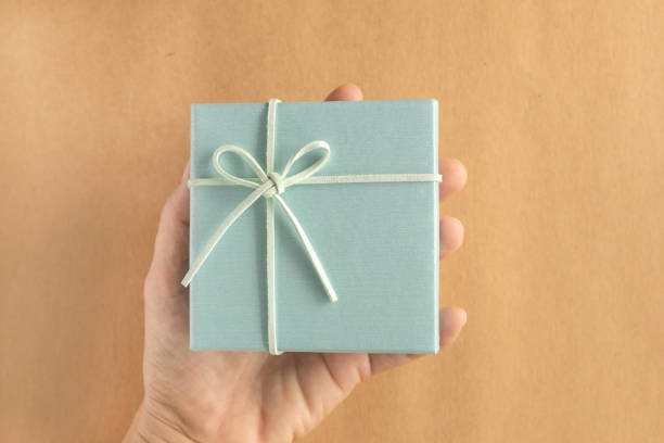 istock Hand of green gift box over brown background. Top view, flat lay with copy space. 2184277419