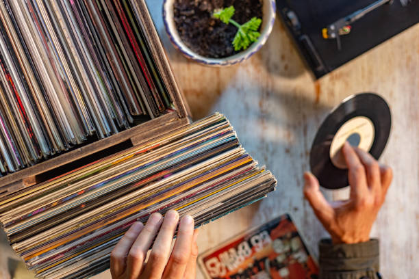 istock High-angle view of a man's hands holding a small vinyl record in a record store, surrounded by boxes of vinyl records 2184277926