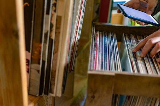 istock View of a man's hands in a record store selecting vinyl records while using his mobile phone to search for them. 2184277932