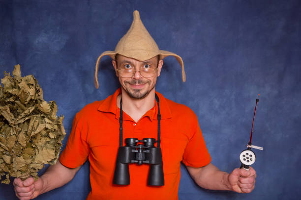 A funny man with a bath broom and a fishing rod in his hands.